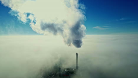 aerial view of power plant with smokestack and fog