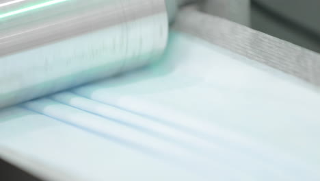 metal roller pressing pleats on a medical mask on process of production line