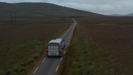 Seguimiento-Hacia-Delante-Del-Coche-Todoterreno-Con-Remolque-De-Caballos-Conduciendo-Por-Una-Carretera-Estrecha-En-El-Campo.-Pastos-Y-Pastizales-A-Lo-Largo-De-La-Carretera.-Irlanda