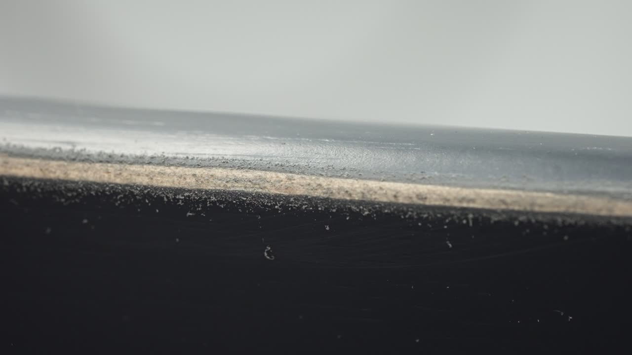 Man’s hand sands edge of chair, stripping grey paint to expose wood beneath