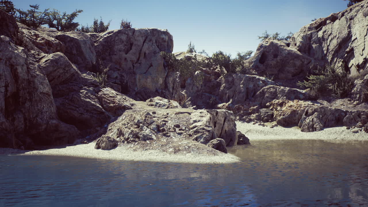 Rocky shoreline with gentle water waves under clear blue sky