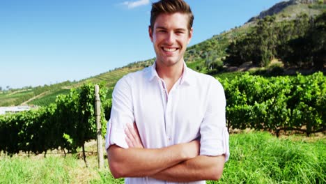 Portrait-of-happy-man-standing-with-arms-crossed-in-vineyard