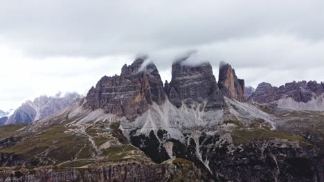 Forward-drone-shot-of-Tre-Cime-di-Lavaredo-from-RIfugio-Auronzo-side-on-cloudy-day