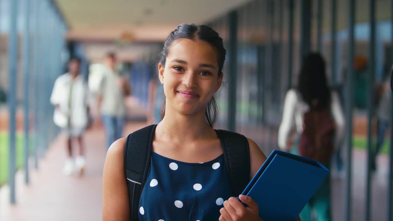 retrato de una estudiante de secundaria o secundaria sonriente con una mochila fuera del salón de clases