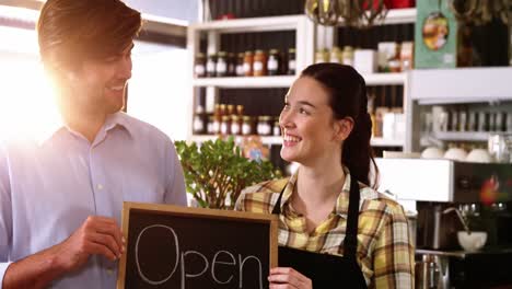 Man-and-waitress-holding-chalkboard-with-open-sign