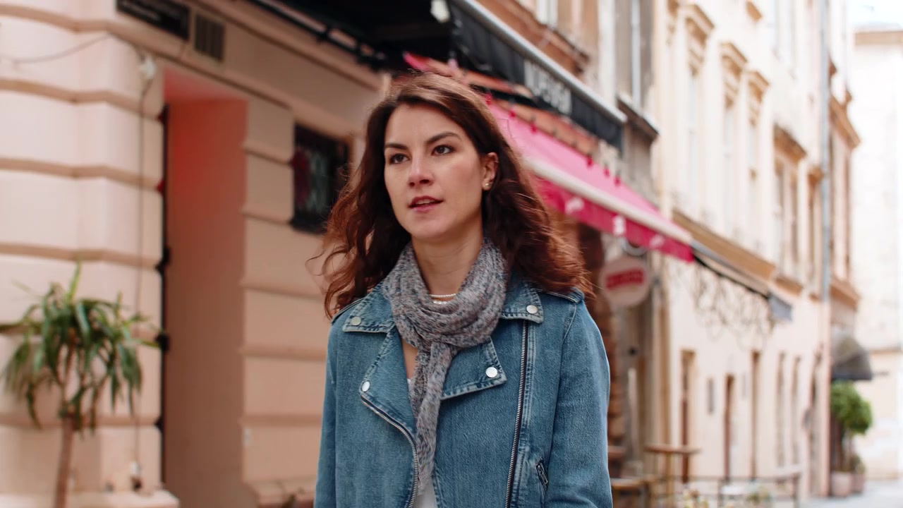 Giovane donna che controlla l'orologio da polso camminando per una strada cittadina, in ritardo per un appuntamento e sentendosi preoccupata per la frenesia urbana.
