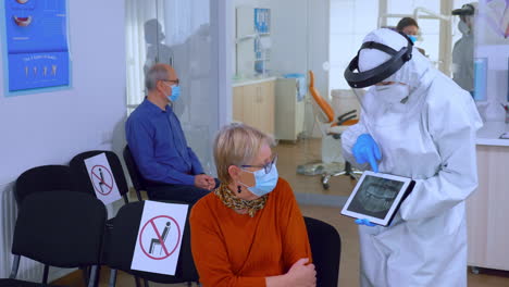 dentist doctor with face shield pointing on tablet display