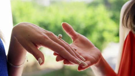 midsection of woman showing engagement ring to friends