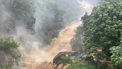 handheld shot of ravana falls at high discharge after heavy rainfall flooding muddy water in ella sri lanka