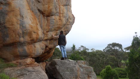 A-bushman-looks-out-accross-the-Australian-outback-while-standing-among-big-craggy-rocky-cliffs