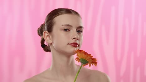 young woman with bright orange flower on vibrant background a serene moment of a woman enjoying the scent of a vibrant orange flower eyes closed in relaxation