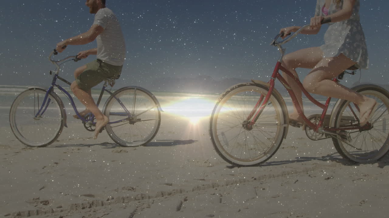 People riding bicycles on beach with sparkling light animation over sunset