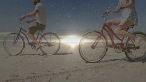 people riding bicycles on beach with sparkling light animation over sunset