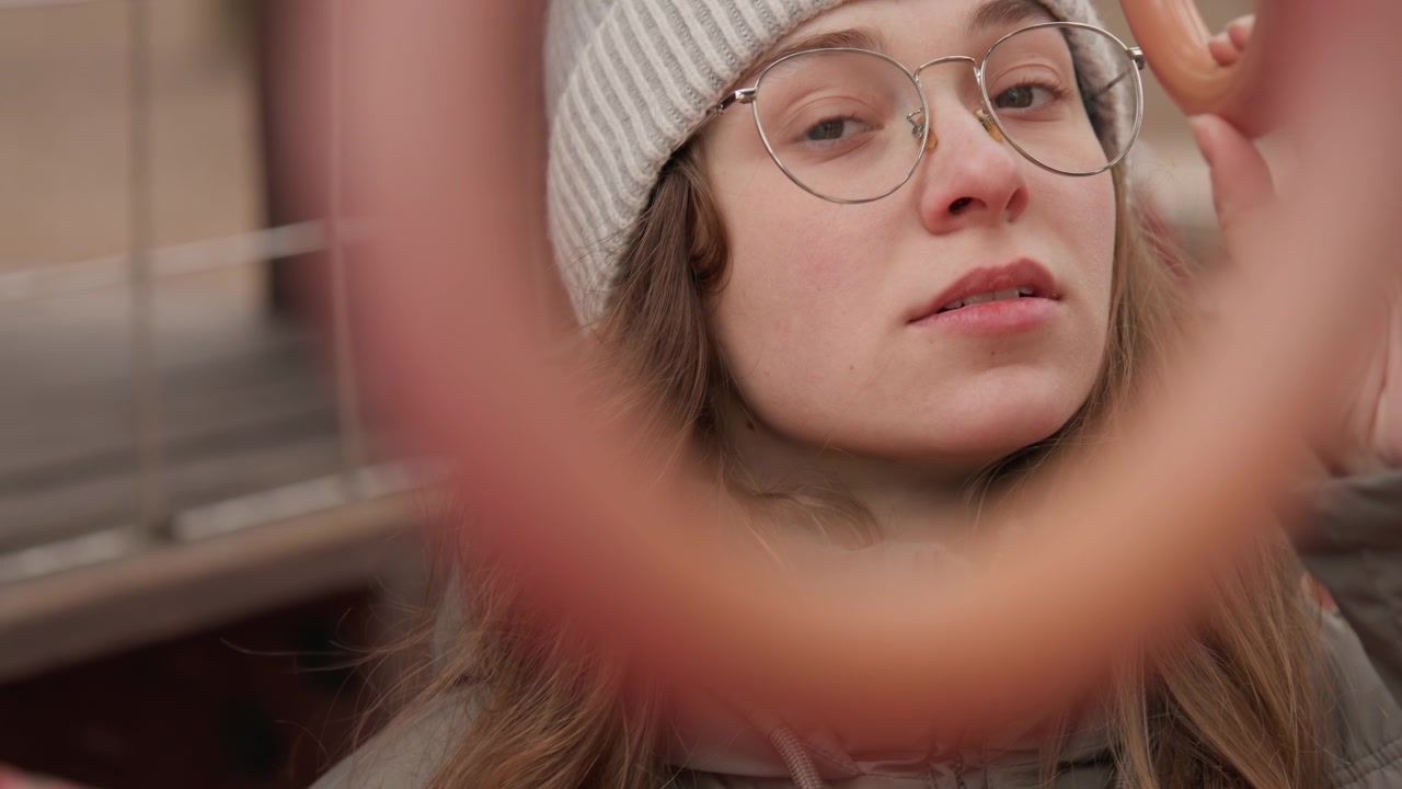 Woman wearing glasses reaches out. Woman with glasses thoughtfully reaches towards surrounding metal circle. Focused woman wearing glasses gently extends her hand towards metal ring structure