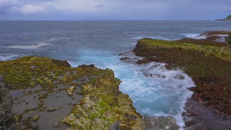 Waves-crashing-on-the-rocky-reef-creating-a-beautiful-foam-pattern-during-a-cloudy-day