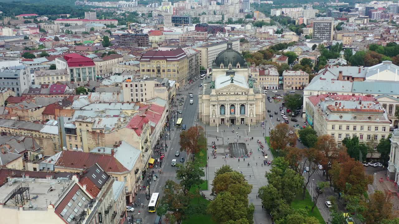 Aerial view of the Lviv National Academic Opera and Ballet Theatre in Lviv Ukraine during a fall day with cars driving and people walking in the square.