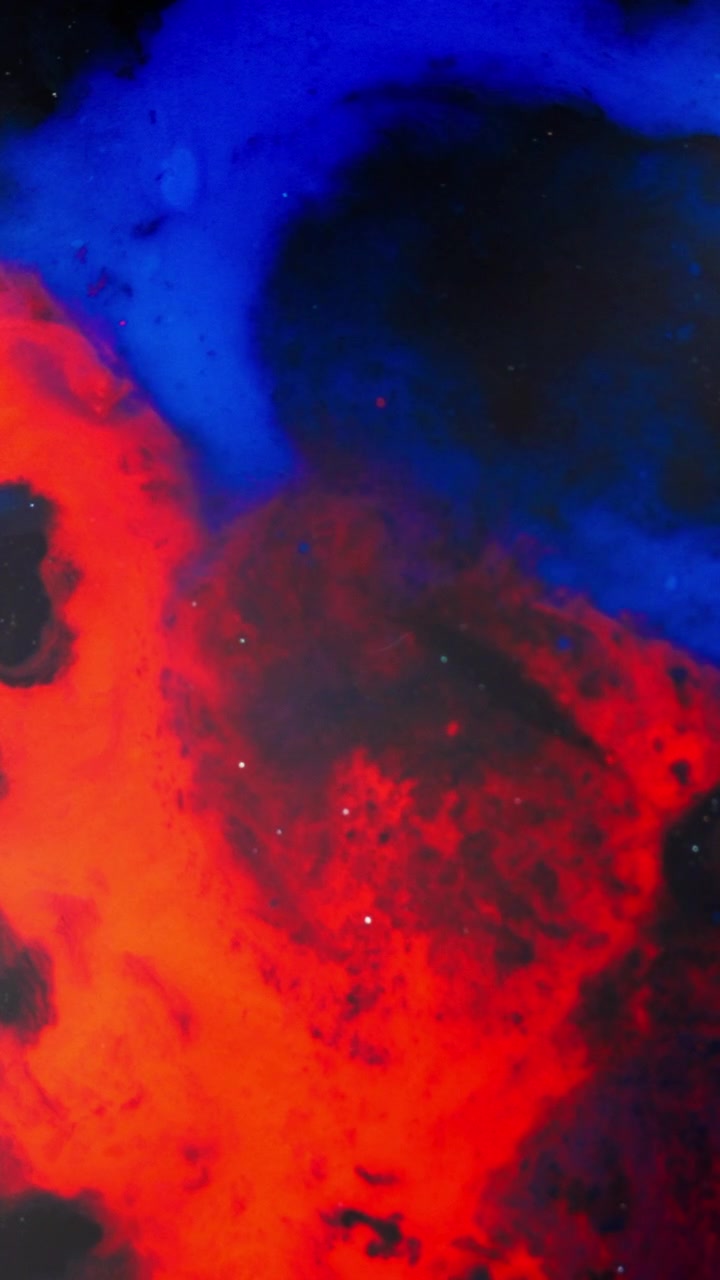 Nuvole vorticose di inchiostro rosso e blu si fondono in un liquido scuro, creando forme astratte cosmiche