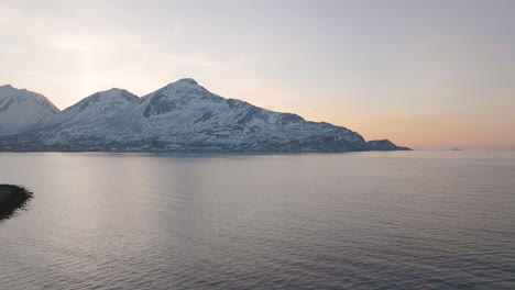 snowy mountains in inhospitable arctic circle, orange glow at sunset