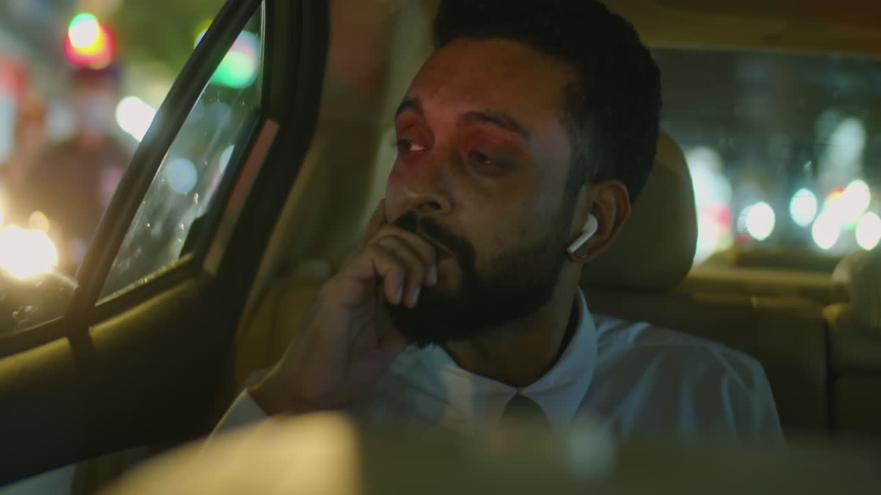 Businessman Putting Earbuds in Taxi at Night