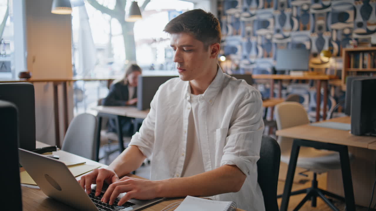 Inspired programmer typing laptop at modern agency closeup. Man at coworking