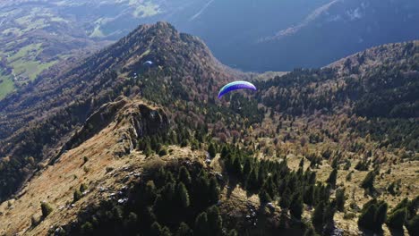 colorful paraglider turns left in the air, adventure sport aerial on dolomites