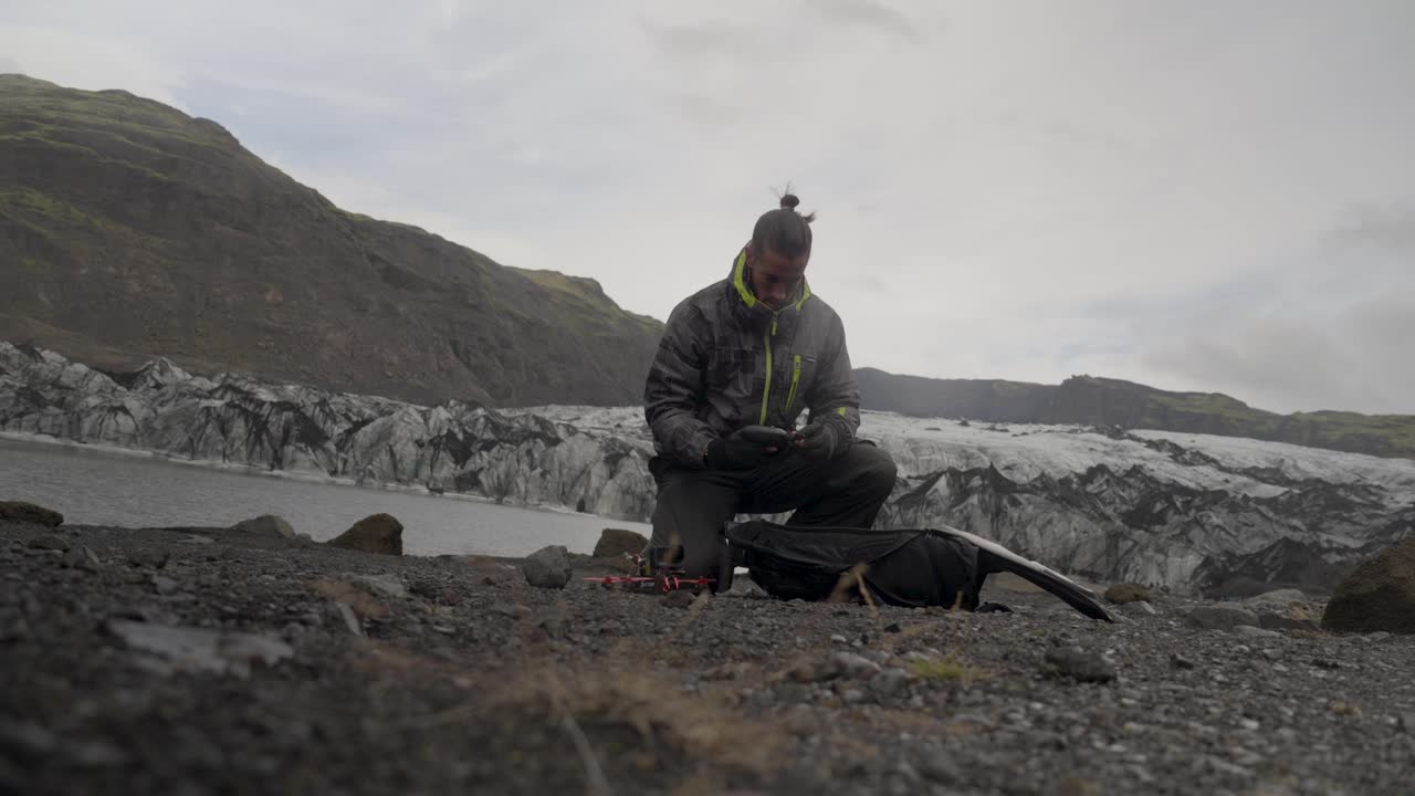 tomada baja de un piloto de fpv preparando su equipo para volar en los glaciares de islandia