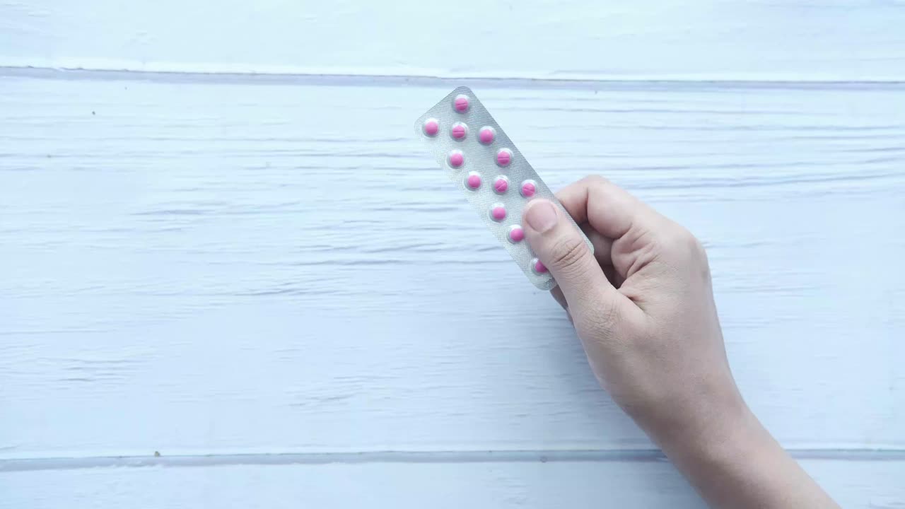 Mano sosteniendo un blíster de pastillas rosas