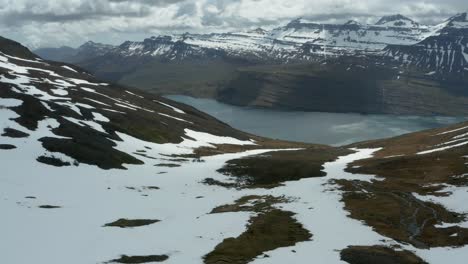 Schmelzender-Schnee-Am-Berghang-In-Island-Mit-Blick-Auf-Den-Fjord-Reyðarfjörður