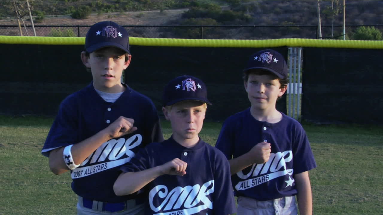 Giovani giocatori di baseball si battono il petto e gesticolano verso il cielo