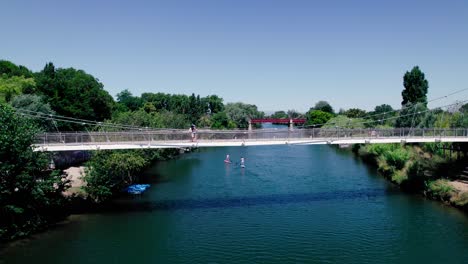 un dron de un pequeño puente colgante en un día soleado en un entorno verde y exuberante