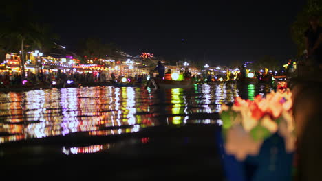 vibrant night scene of a river with boats, floating lanterns, and city lights reflections
