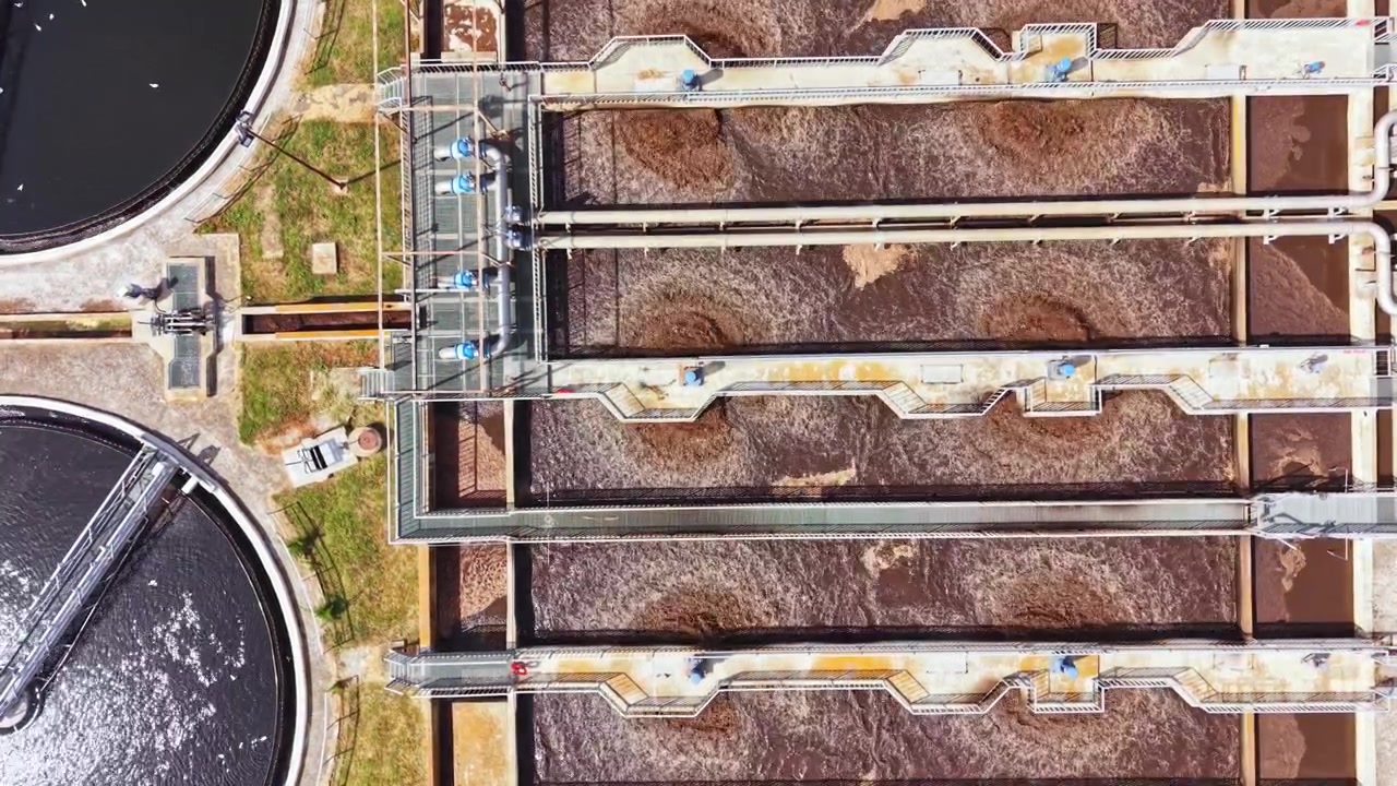 Large wastewater treatment facility showing several treatment tanks and equipment under clear sky during daylight hours