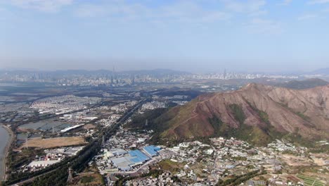 Hong-Kong-and-Shenzhen-border-line-over-Hong-Kong-rural-houses-with-Shenhzen-skyline-in-the-horizon,-Aerial-view