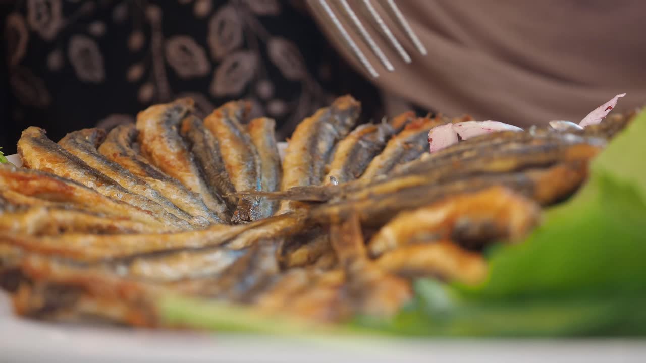 A close-up view of a plate of crispy fried fish with green garnish