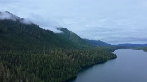 Aerial-view-of-foggy-Pacific-Northwest-Mountain-Forest-meeting-scenic-lake