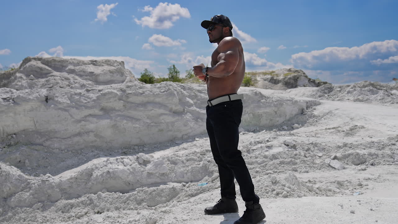Muscular man with naked torso. Male bodybuilder with naked torso posing on the rock