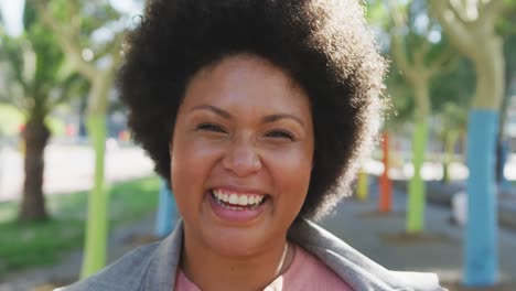 portrait of happy plus size biracial woman smiling in park