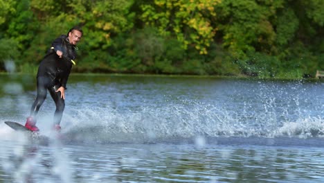 handsome man wakesurfing in water splashes. young man riding wakeboard