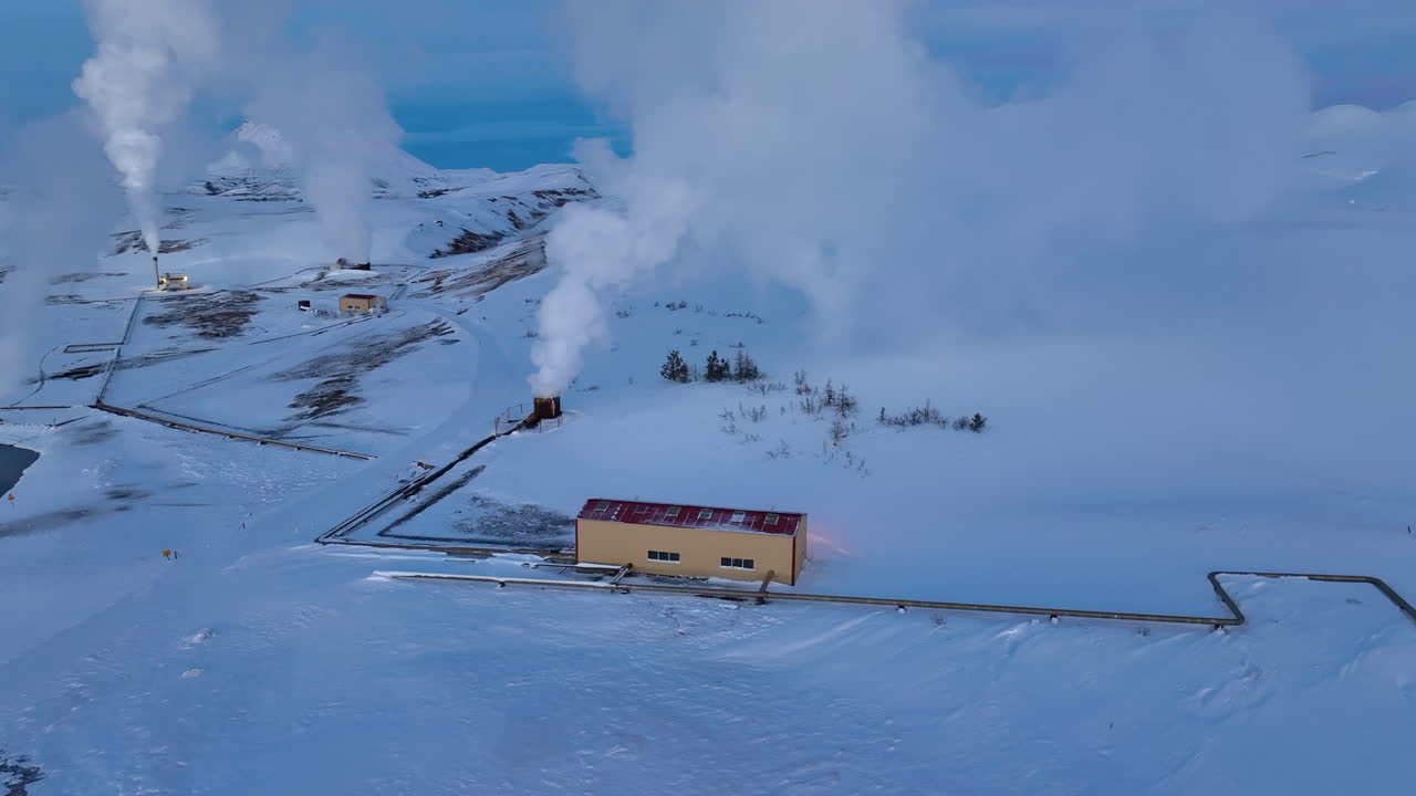 저녁에 아이슬란드의 하얀 눈 덮인 풍경에 있는 지열 설비에서 흰 연기가 난다