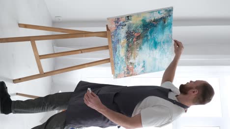 vertical video artist uses talent and tie dye to create a masterpiece on canvas in workshop