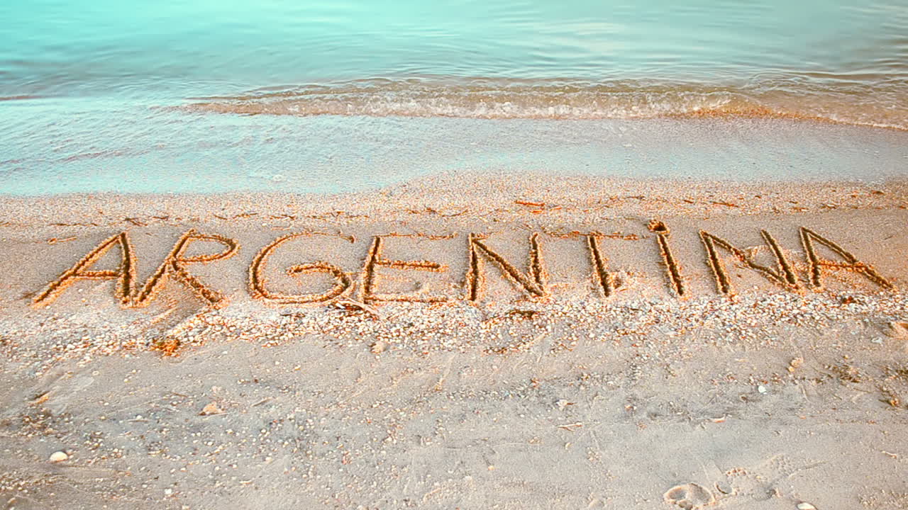 Inskriptionen 'Argentina' i sanden. Inskription på sand, stranden.