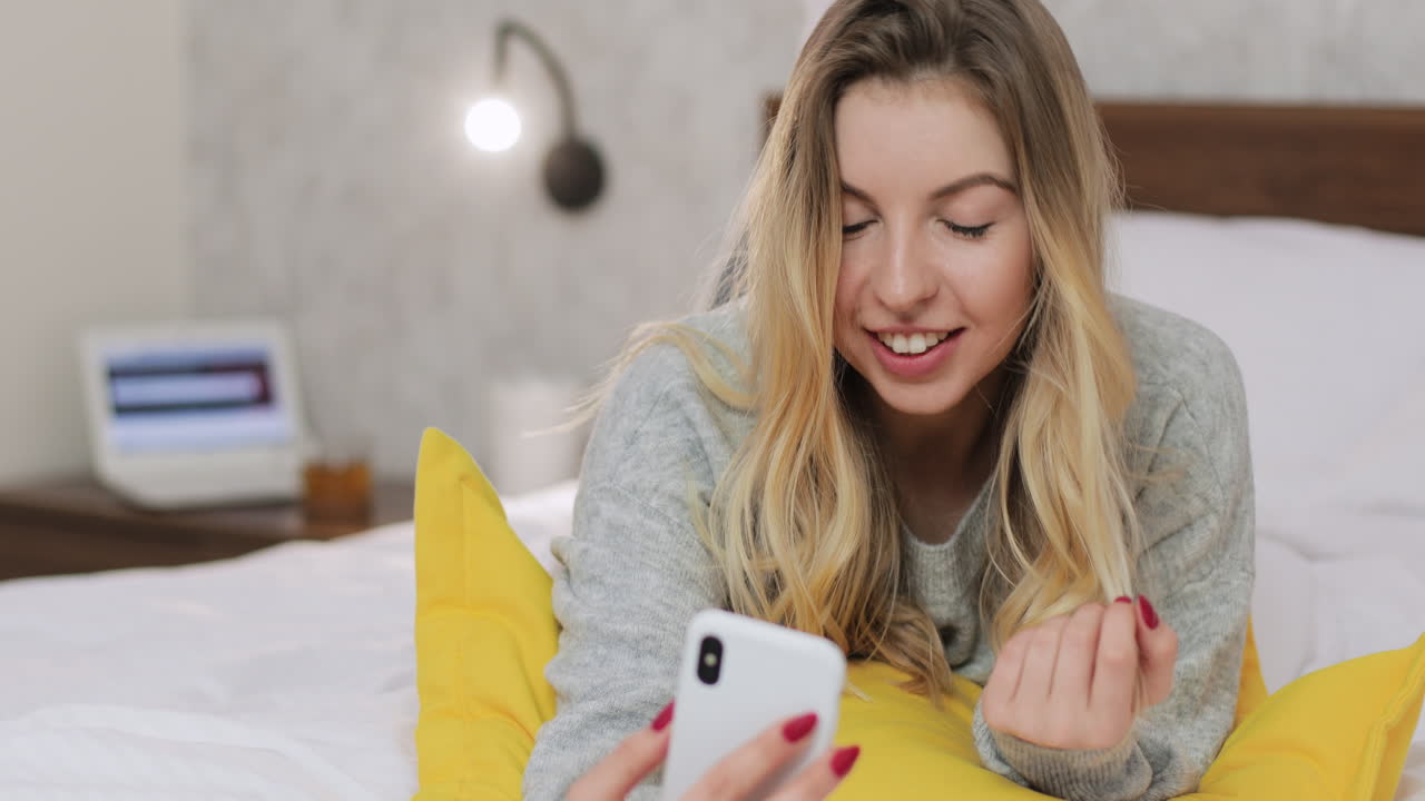 스마트폰을 사용하여 침대에서 휴식을 취하는 여성