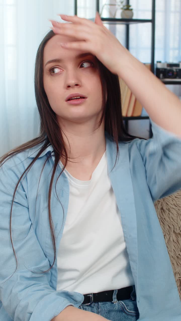 Young woman on sofa upset disappointed doing facepalm gesture frustrated unhappy with mistake