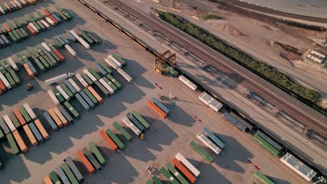 Beeindruckende-Luftaufnahme-Eines-Containerstaplers,-Der-über-Aufgereihten-Containern-Fährt
