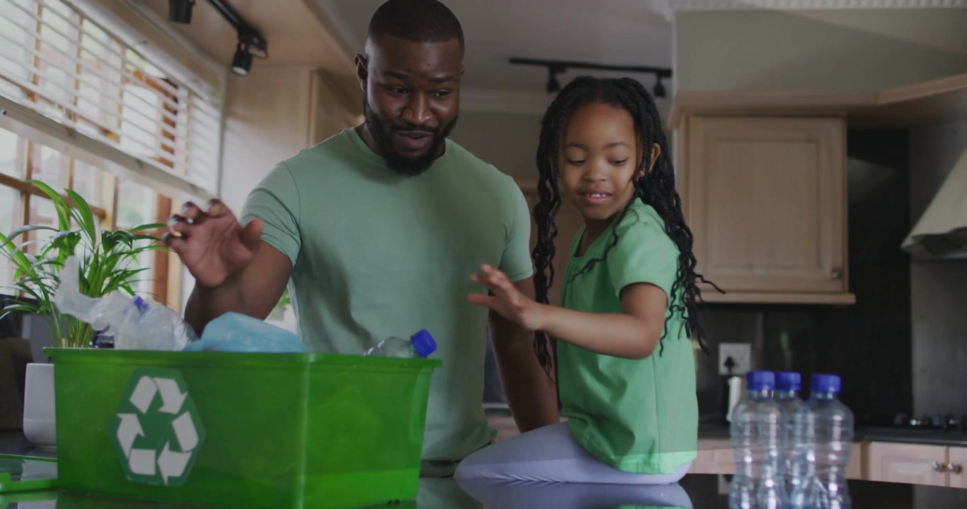 Dad teaching girl at counter, dropping bottles into green bin while code overlay fading, recycling