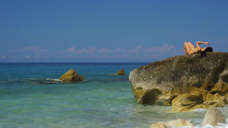 Mujer-Joven-Tendida-En-Un-Gran-Acantilado-Bañada-Por-Agua-Esmeralda-Cristalina-Del-Mar-Mediterráneo-Azul-Turquesa