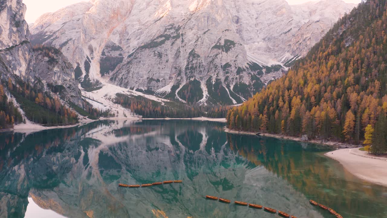 Carrellata aerea verticale rivela l'iconico Lago di Braies nelle Dolomiti italiane in una giornata autunnale