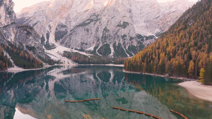 Carrellata aerea verticale rivela l'iconico Lago di Braies nelle Dolomiti italiane in una giornata autunnale