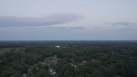 Un-Dron-Aéreo-Se-Disparó-Hacia-Adelante-Sobre-Una-Ciudad-Rodeada-De-Exuberante-Vegetación-Durante-La-Noche