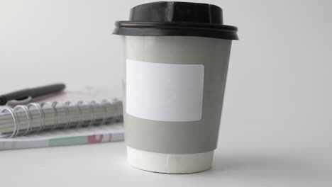 coffee cup on a desk with notebook and pen